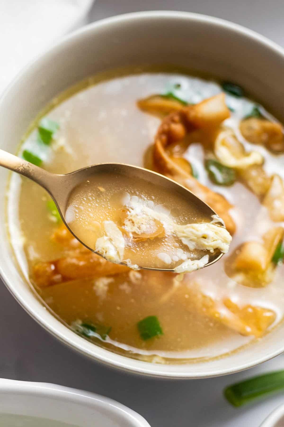 spoonful of broth and egg ribbons from a bowl of egg drop soup