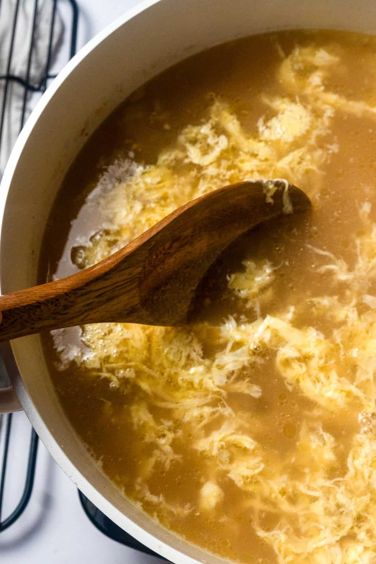 eggs being stirred into the hot broth