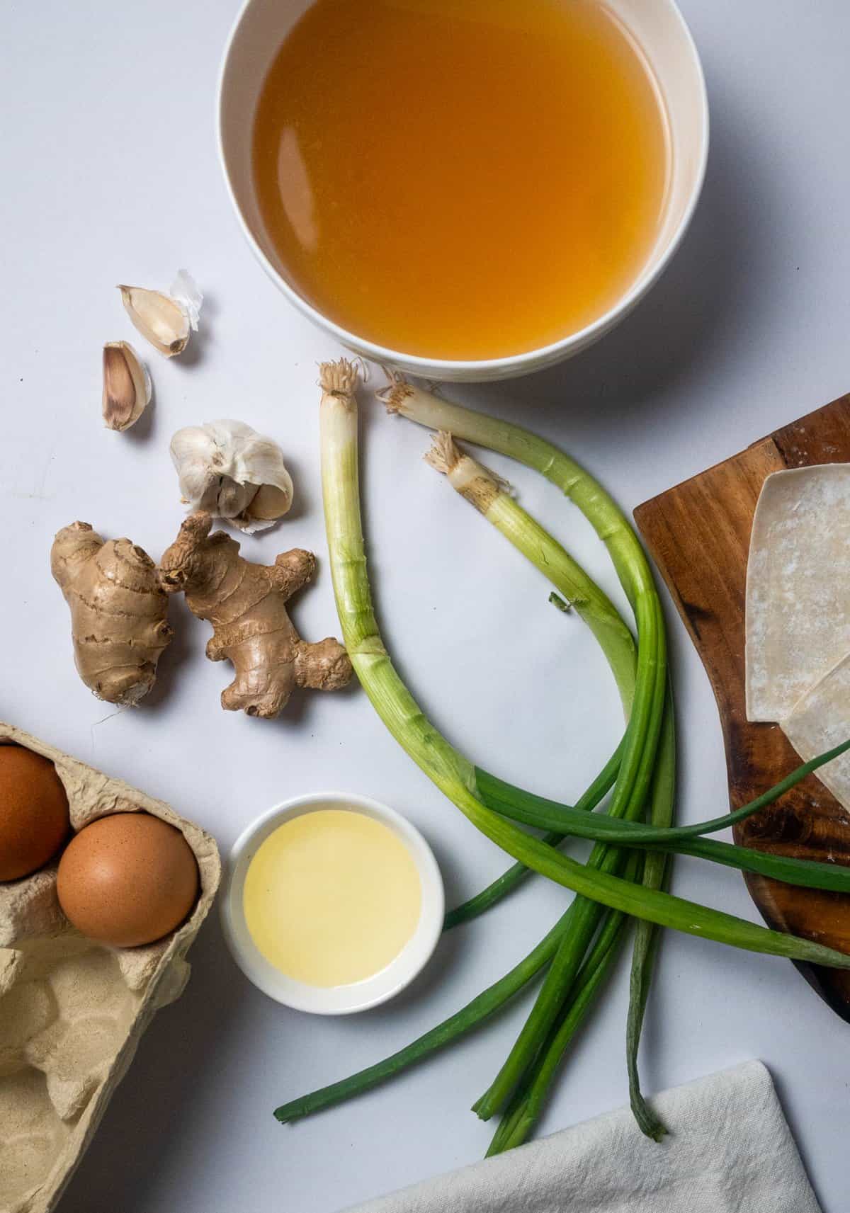 green onion, ginger, garlic, eggs, broth on a table
