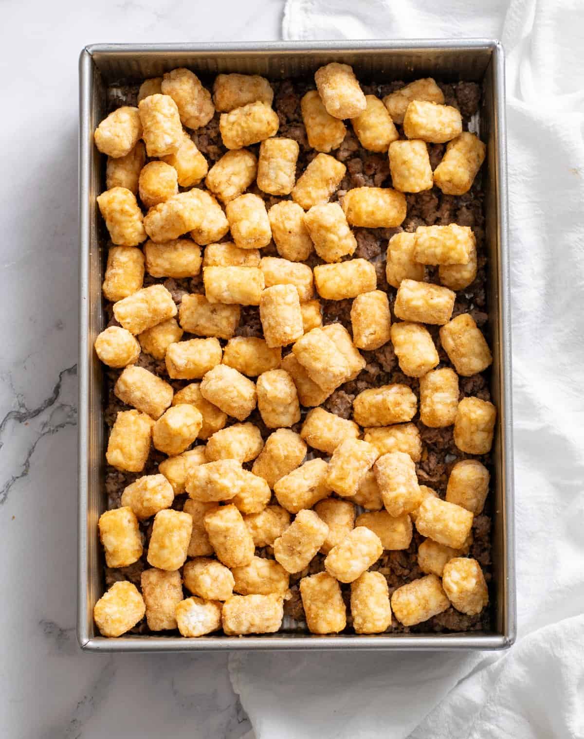 frozen tater tots on top of the sausage