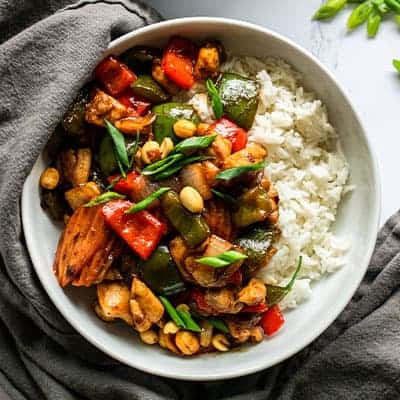 bowl of kung pao chicken with peppers, and carrots over rice