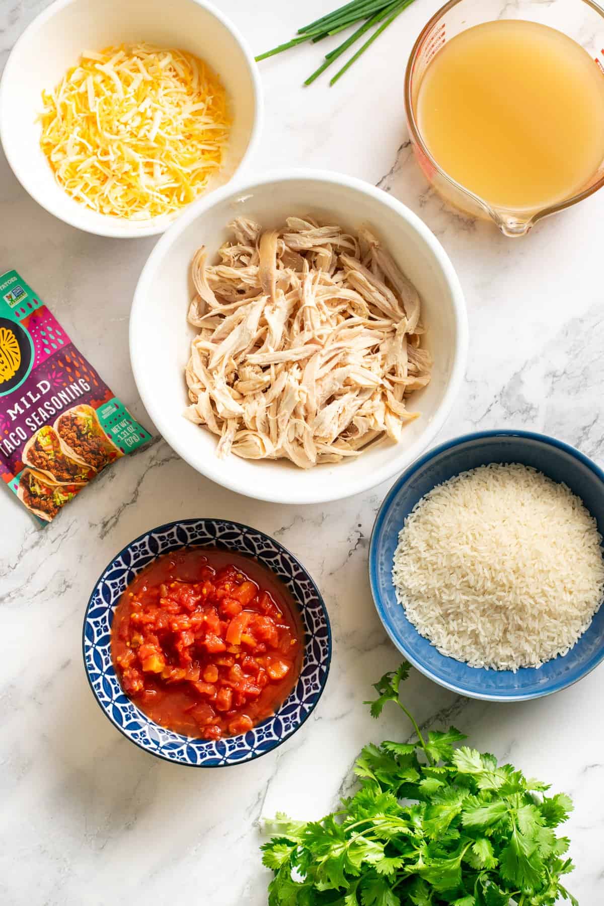 bowls of shredded chicken, canned tomato, shredded cheese, broth, and uncooked rice