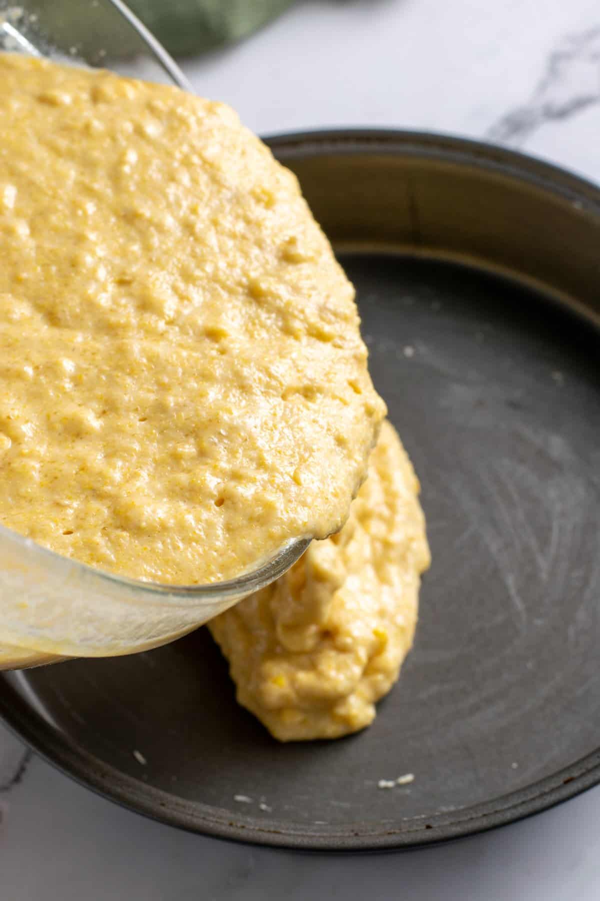 cornbread batter being poured in a greased pan